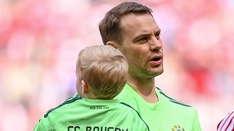 Manuel Neuer und Sohn Luca Manuel Neuer im hellgrünen Trikot des FC Bayern München steht auf dem Spielfeld und hält sein Sohn im passenden Bayern-Trikot auf dem Arm.