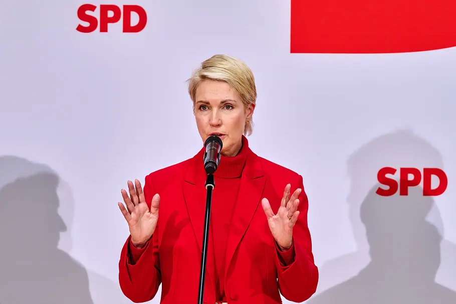 Manuela Schwesig Manuela Schwesig spricht mit erhobenen Händen in ein Mikrofon vor einer Wand mit SPD-Logos.