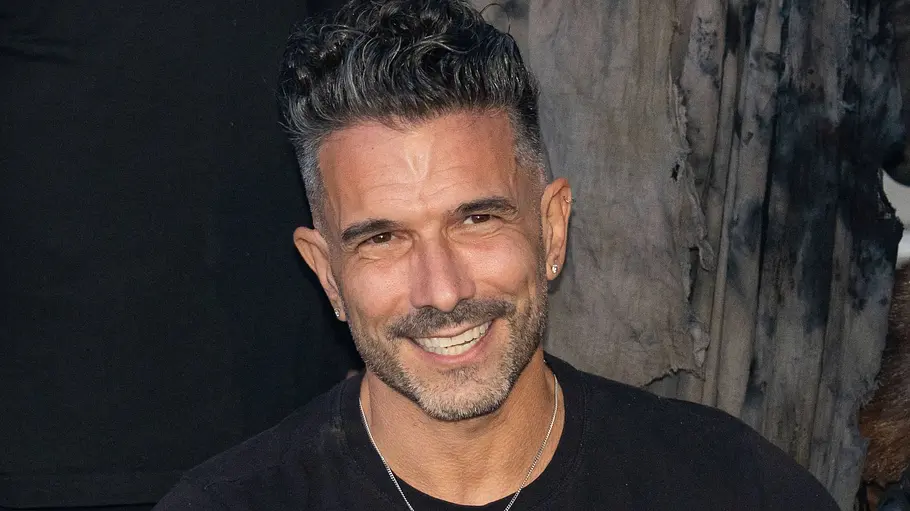 Marc Terenzi: Ein lächelnder Mann sitzt zwischen Personen in Zombie-Maskerade vor einer roten Torte mit Handdekorationen und Kerzen.