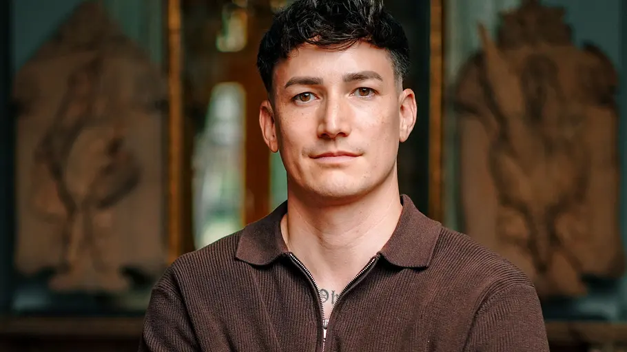 Marcel Nguyen ist Kunstturner. Marcel Nguyen mit verschränkten Armen hinter einem Stuhl.