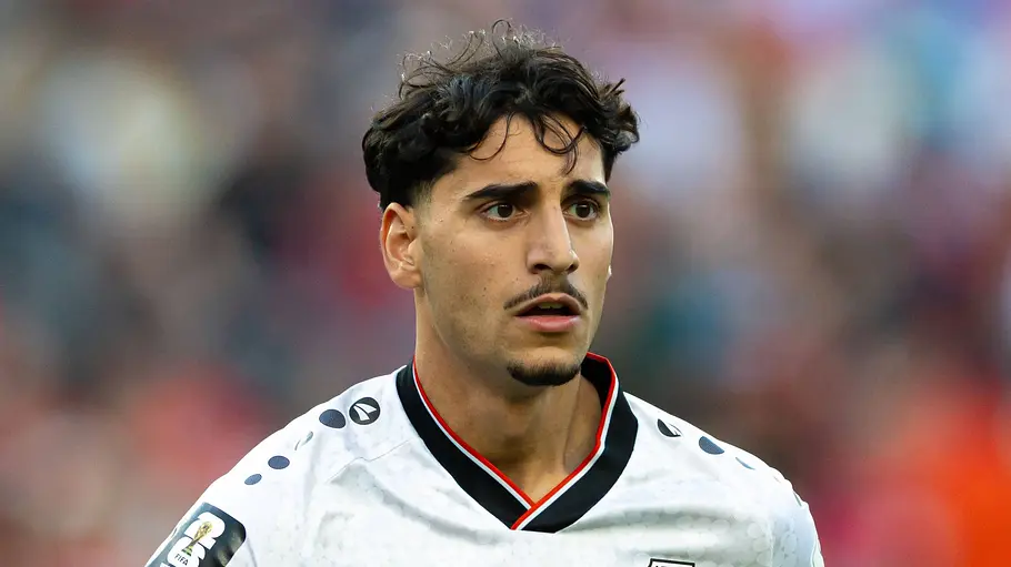 Irakischer Nationalspieler im weißen Trikot mit der Rückennummer 21 läuft während eines Länderspiels über den Platz. Im Hintergrund sind die Zuschauer auf der Tribüne unscharf zu sehen.