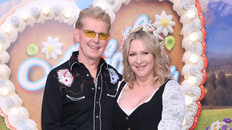 Markus Mörl und Yvonne König Markus Mörl und Yvonne König stehen lächelnd in Trachtenkleidung vor einer Kulisse mit Lebkuchenherzen und halten sich an den Händen.