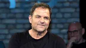 Martin Rütter im schwarzen Oberteil lächelt leicht. Hinter ihm sitzt unscharf ein Mann mit Brille vor einer blau beleuchteten Wand. - Foto: Imago/Stefan Schmidbauer Martin Rütter im schwarzen Oberteil lächelt leicht. Hinter ihm sitzt unscharf ein Mann mit Brille vor einer blau beleuchteten Wand. - Foto: Imago/Stefan Schmidbauer