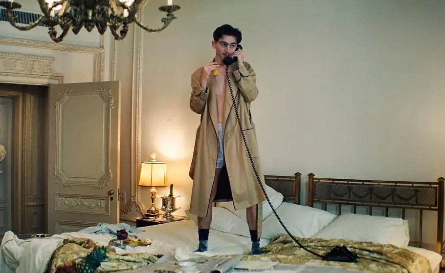 Timothée Chalamet als Marty Mauser stehend auf einem Bett.