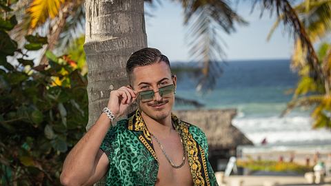 Marvin Kleinen rückt seine Sonnenbrille zurecht. Hinter ihm traumhafte Meereskulisse - Foto: RTL / Frank Fastner