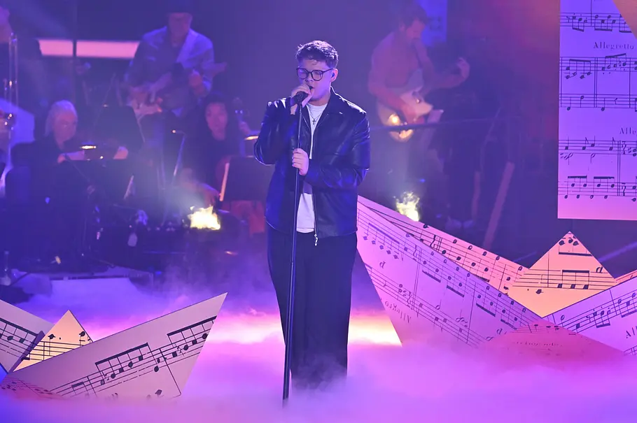 Marvin Tapper Halbfinale The Voice 2025 Marvin tapper performt im Halbfinale. Auf der Bühne sind Papierschiffe mit Musiknoten drauf.