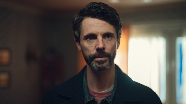 Carl Morck schaut leicht beunruhigt nach links, der Hintergrund ist unscharf. - Foto: Justin Downing/Netflix