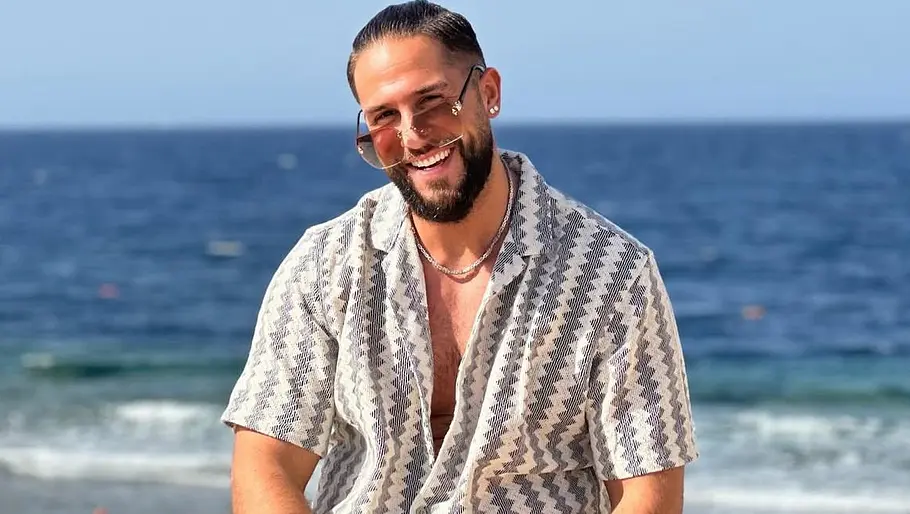Maurice Dziwak lächelnd vor dem Meer Maurice Dziwak sitzt lächelnd auf einem Geländer vor dem Meer