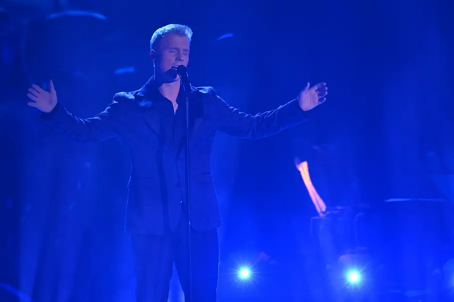 Max Pesé Halbfinale The Voice 2025 Max Pesé performt im Halbfinale in einem schwarzen Anzug. Beim Singen hat er die Arme zur Seite ausgebreitet.