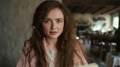 Sybylla sitzt an ihrer Schreibmaschine. - Foto: © 2026 Netflix, Inc.