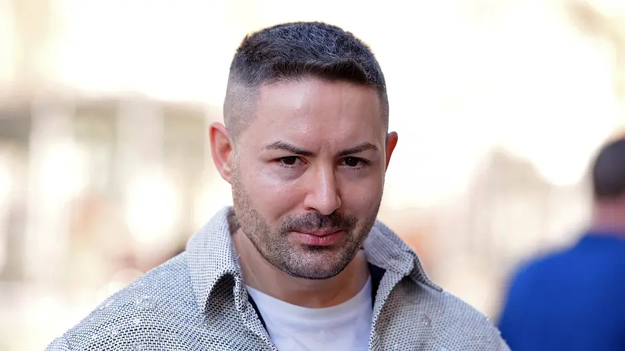 Menderes Bagci bei Promis unter Palmen Menderes Bagci lächelt schüchtern in die Kamera.