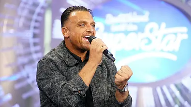 Menowin Fröhlich singt mit ausdrucksstarker Mimik in ein Handmikrofon auf der Bühne von „Deutschland sucht den Superstar“. - Foto: RTL / Stefan Gregorowius