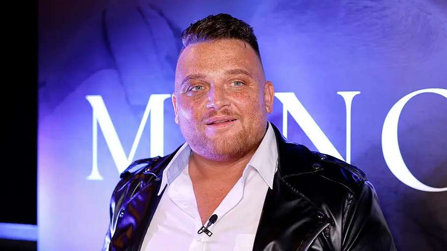 Menowin Fröhlich muss sich von den DSDS-Fans kritisieren lassen. Menowin Fröhlich trägt ein weißes Hemd und eine schwarze Lederjacke. An seinem Kragen ist ein kleines Mikrofon befestigt.