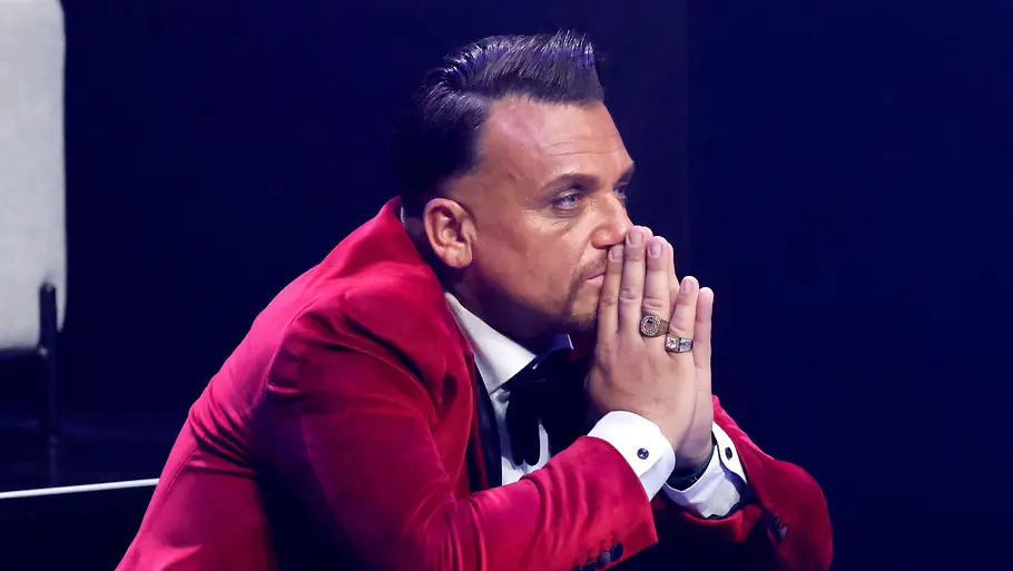 Menowin Fröhlich Menowin Fröhlich sitzt und presst seine Hände vor dem Mund zusammen. Er sieht ernst aus.