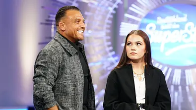 Menowin Fröhlich und seine Tochter stehen gemeinsam im DSDS-Studio auf der Bühne, sie hält ein Mikrofon in der Hand. - Foto: RTL / Stefan Gregorowius