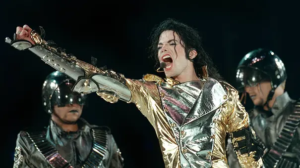 Michael Jackson streckt voller Inbrunst den Arm nach oben. Um ihn herum stehen zwei Männer. - Foto:  IMAGO / Kamerapress