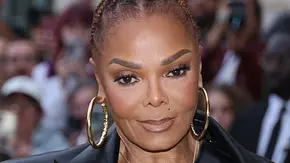 Janet Jackson, komplett in schwarz gekleidet, trägt einen hohen Dutt und große, goldene Creolen. - Foto: IMAGO / Bestimage