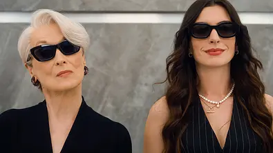 Miranda und Andy mit Sonnenbrillen stehen selbstbewusst nebeneinander vor einer grauen Wand und blicken direkt in die Kamera. - Foto: IMAGO / Landmark Media Miranda und Andy mit Sonnenbrillen stehen selbstbewusst nebeneinander vor einer grauen Wand und blicken direkt in die Kamera. - Foto: IMAGO / Landmark Media