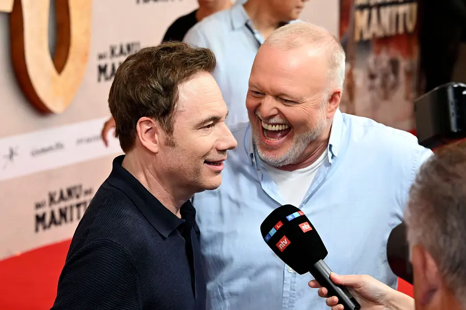 Mit diesem Gesichtsaudruck würde Stefan Raab natürlich keine 10 Sekunden aushalten. Stefan Raab und Michael Herbig werden am roten Teppich interviewt, Raab lacht.