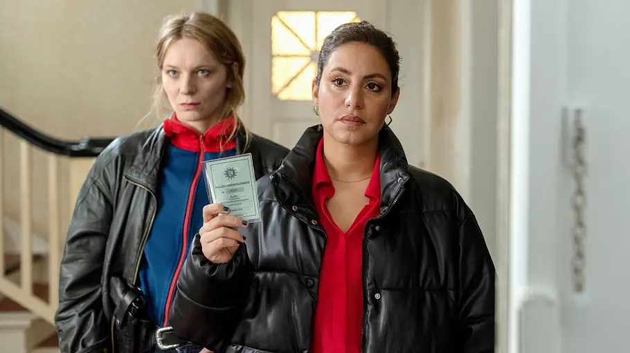 Mit Mila und Anna Nowak geht es schon nächsten Sonntag weiter. Mila und Anna Nowak stehen im Treppenhaus. Letztere trägt eine schwarze Steppjacke und zeigt einen Polizeiausweis.
