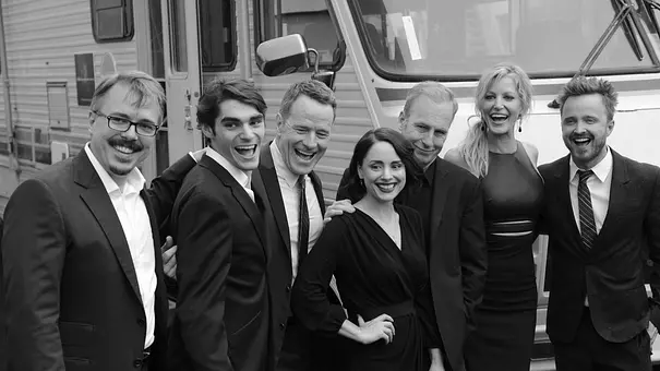 Vince Gilligan, RJ Mitte und die Besetzung von „Breaking Bad“ posieren lachend vor einem Wohnmobil. Die Aufnahme ist schwarz-weiß. - Foto: IMAGO / UPI Photo