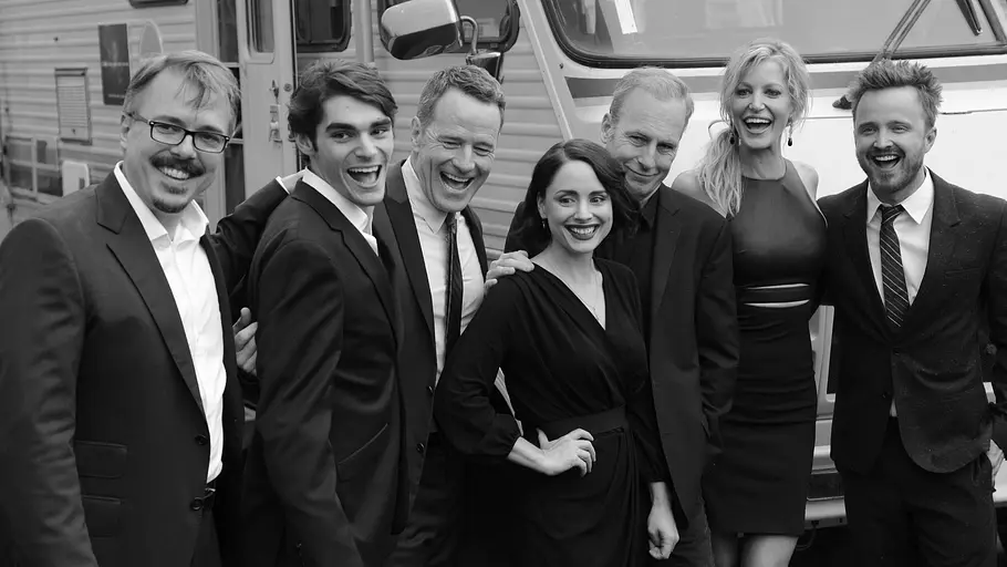 Mit vielen „Breaking Bad“-Stars hatte RJ Mitte noch ein enges Verhältnis. Vince Gilligan, RJ Mitte und die Besetzung von „Breaking Bad“ posieren lachend vor einem Wohnmobil. Die Aufnahme ist schwarz-weiß.