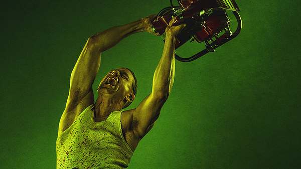 Charlie Hunnam schwingt als Ed Gein eine Kettensäge durch die Luft. Er trägt ein weißes Tank-Top und eine schwarze Hose. - Foto: Netflix