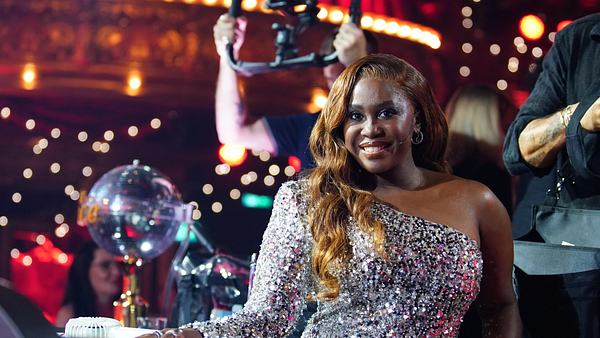 Die „Lets Dance“ Jurorin Motsi Mabuse blickt freundlich in einem schönen Abendkleid in die Kamera, während sie im Studio sitzt. - Foto: RTL Deutschland