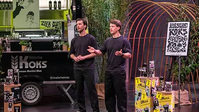Maximilian Koeser (links) und Nicolas Lutz stehen vor einem Getränkestand mit Flaschen und Werbung für „Kölsche Koks“. - Foto: RTL / Bernd-Michael Maurer Maximilian Koeser (links) und Nicolas Lutz stehen vor einem Getränkestand mit Flaschen und Werbung für „Kölsche Koks“. - Foto: RTL / Bernd-Michael Maurer
