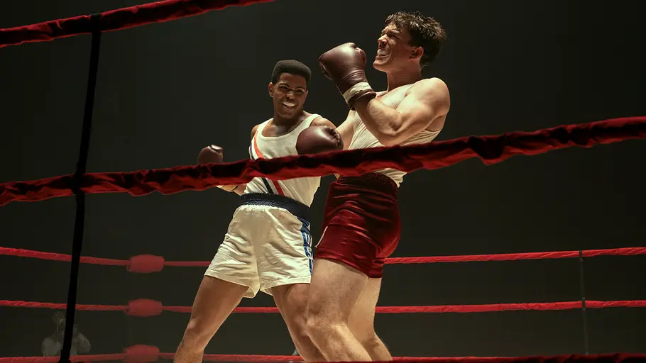 Muhammad Ali in weißen Shorts boxt gegen einen Gegner in roten Shorts. Rote Ringseile verlaufen vor den beiden Boxern.