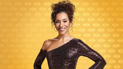 Nadja Benaissa lächelt mit hochgesteckten Locken im dunklen, schulterfreien Paillettenkleid vor gelb gemustertem Hintergrund. - Foto: Marc Rehbeck/ Joyn Nadja Benaissa lächelt mit hochgesteckten Locken im dunklen, schulterfreien Paillettenkleid vor gelb gemustertem Hintergrund. - Foto: Marc Rehbeck/ Joyn