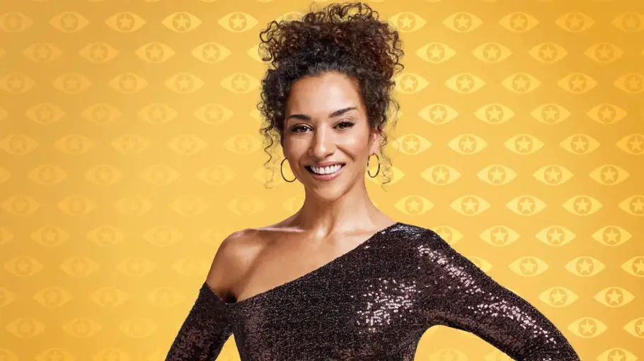 Nadja Benaissa: „Promi Big Brother“-Abbruch wegen Redo – „Grenzüberschreitung“ Nadja Benaissa lächelt mit hochgesteckten Locken im dunklen, schulterfreien Paillettenkleid vor gelb gemustertem Hintergrund.
