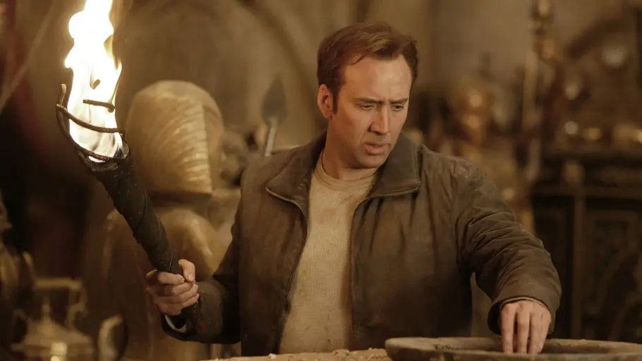 National Treasure Ben Gates hält eine Fackel und untersucht eine Schatzkammer.