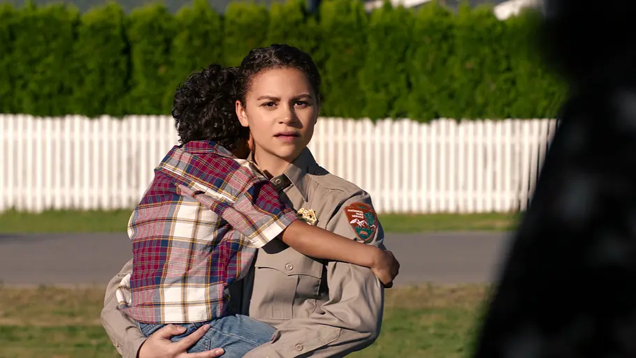 Lily Santiago als Naya Vasquez, sie hält ein Kind auf dem Arm.