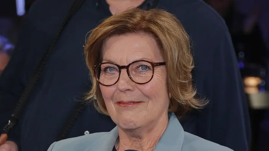 Dora Heldt sitzt in einem Sessel im NDR-Studio, trägt einen hellblauen Hosenanzug und blickt lächelnd in die Kamera.