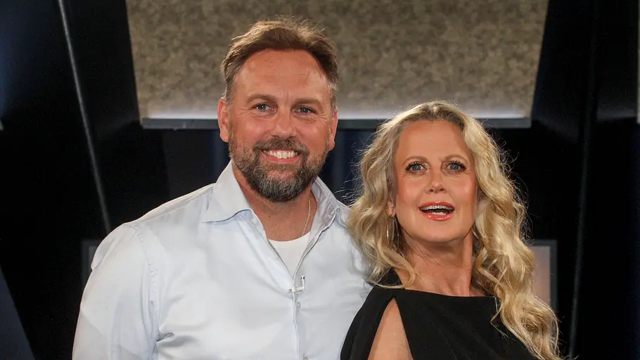 Barbara Schöneberger und Steven Gätjen Barbara Schöneberger und Steven Gätjen stehen nebeneinander und lächeln in die Kamera; sie trägt ein schwarzes Kleid, er ein helles Hemd, im Hintergrund ist eine dunkle Studio-Kulisse.