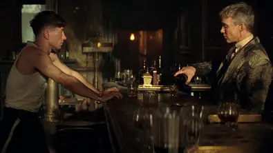 Tommy und Duke Shelby sitzen im Garrison. Tommy schenkt sich einen Drink ein und wird dabei von seinem Sohn beobachtet. - Foto: Netflix