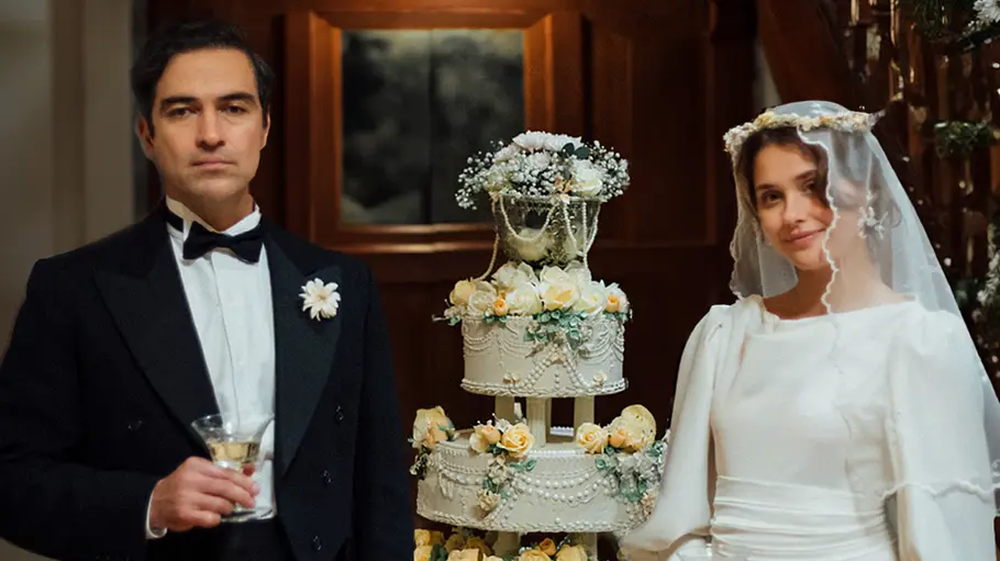 Clara del Valle im Hochzeitskleid und ein Mann. Zwischen ihnen steht eine Hochzeitstorte.