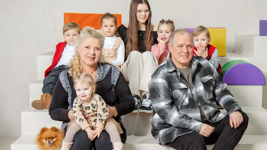 Die Wollnys: Neuer Sendeplatz Die Wollnys: Silvia Wollny und Harald sitzen mit sechs Enkeln und Sarafinas Hund auf weißen Stufen vor bunten Polstern.