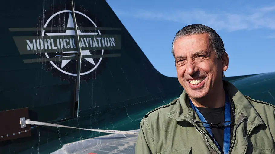 Neue Staffel „Morlock Motors“ 2026. Michael Manousakis in grüner Fliegerjacke steht vor einem Flugzeugheck mit der Aufschrift „Morlock Aviation“.