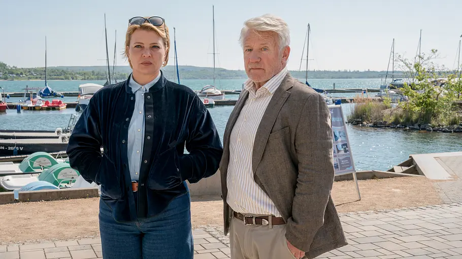 Neues Land ZDF Film Ina Sedlitz (Jördis Triebel) und Walter Sedlitz (Jörg Schüttauf) stehen nebeneinander an einem gepflasterten Uferweg