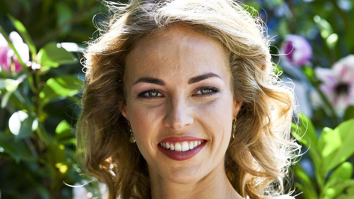 Ella aus die Landarztpraxis lächelt in einem Blumenkleid in die Kamera