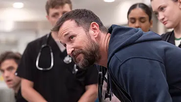 Noah Wyle steht über einem Patienten mit seinem jungen Ärzte-Team. - Foto: HBO Max