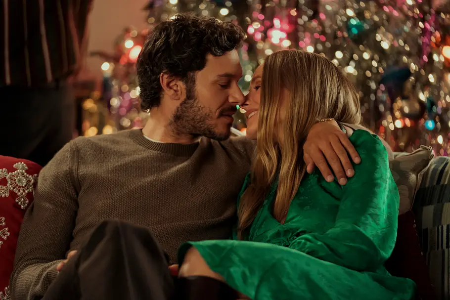 Noah und Joanne verloben sich Noah und Joanne sitzen eng umschlungen auf einem Sofa und lächeln einander an. Im Hintergrund glitzert Weihnachtsschmuck.
