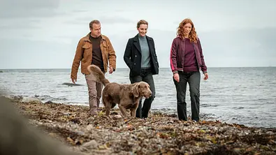 auke Jacobs (Hinnerk Schönemann), mit Hund Holly (Fritz), Hannah Wagner (Jana Klinge) und Jule Christiansen (Marleen Lohse) am Strand von Schwanitz (v.l.). - Foto: NDR/Gordon Timpen