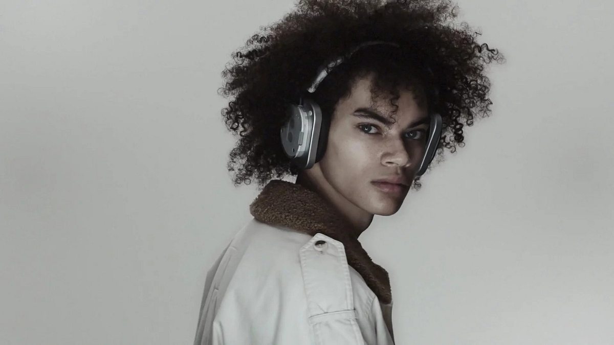 Nothing Headphone (1) Man mir Locken und Nothing Headphone (1) schaut über seine Schulter in die Kamera.