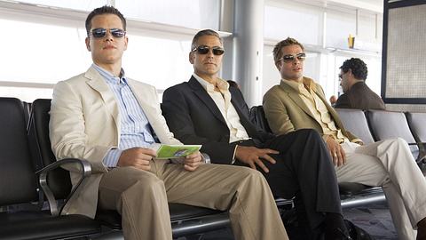 Matt Damon, George Clooney und Brad Pitt sitzen in Oceans 13 am Flughafen und blicken in die Ferne - Foto: Warner Bros.