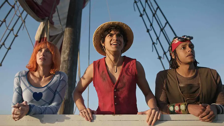 Ein Mädchen und zwei Jungs stehen auf einem Piratenschiff und schauen in „One Piece“ Richtung Horizont.