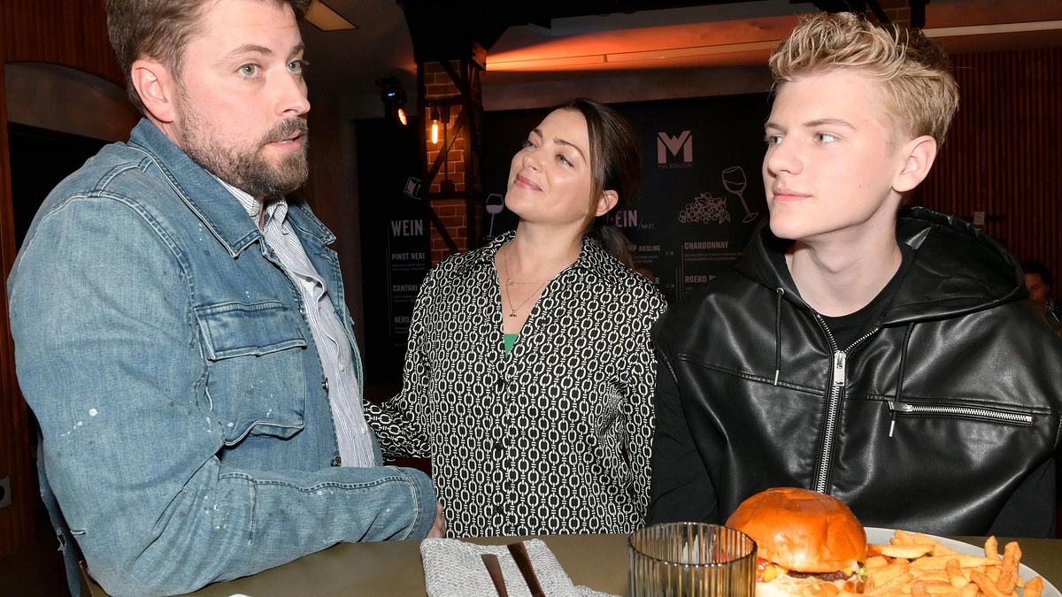Oskar ist wieder da! John mit kritischem Gesicht, Emily am lächeln und Oskar an der Bar.