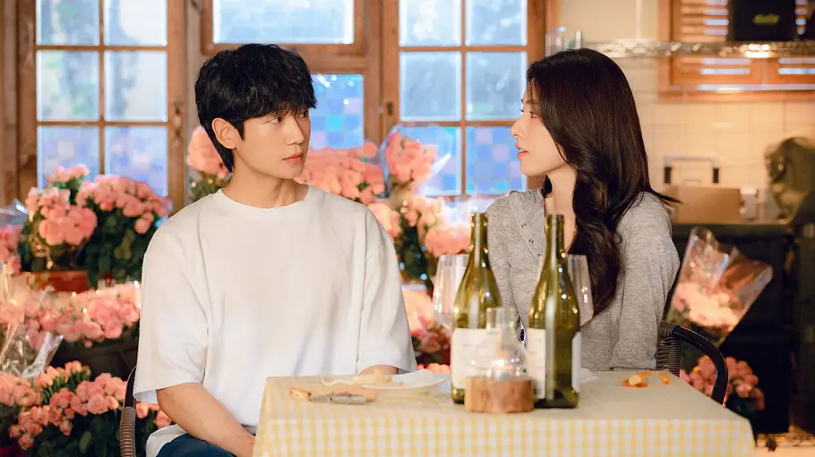 Tae-ha und Eun-sae Tae-ha und Eun-sae sitzen an einem Tisch mit Wein. Hinter ihnen sich viele rosa Blumen.